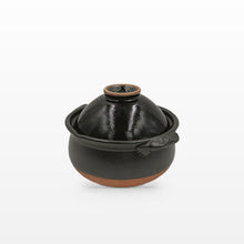 A small black glazed ceramic lidded pot with a brown unglazed base and rim, shown on a clean white background.