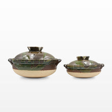 Two handmade ceramic lidded pots with side handles, one large and one small, featuring a green and brown glazed upper half and a speckled beige lower half, set against a plain white background.